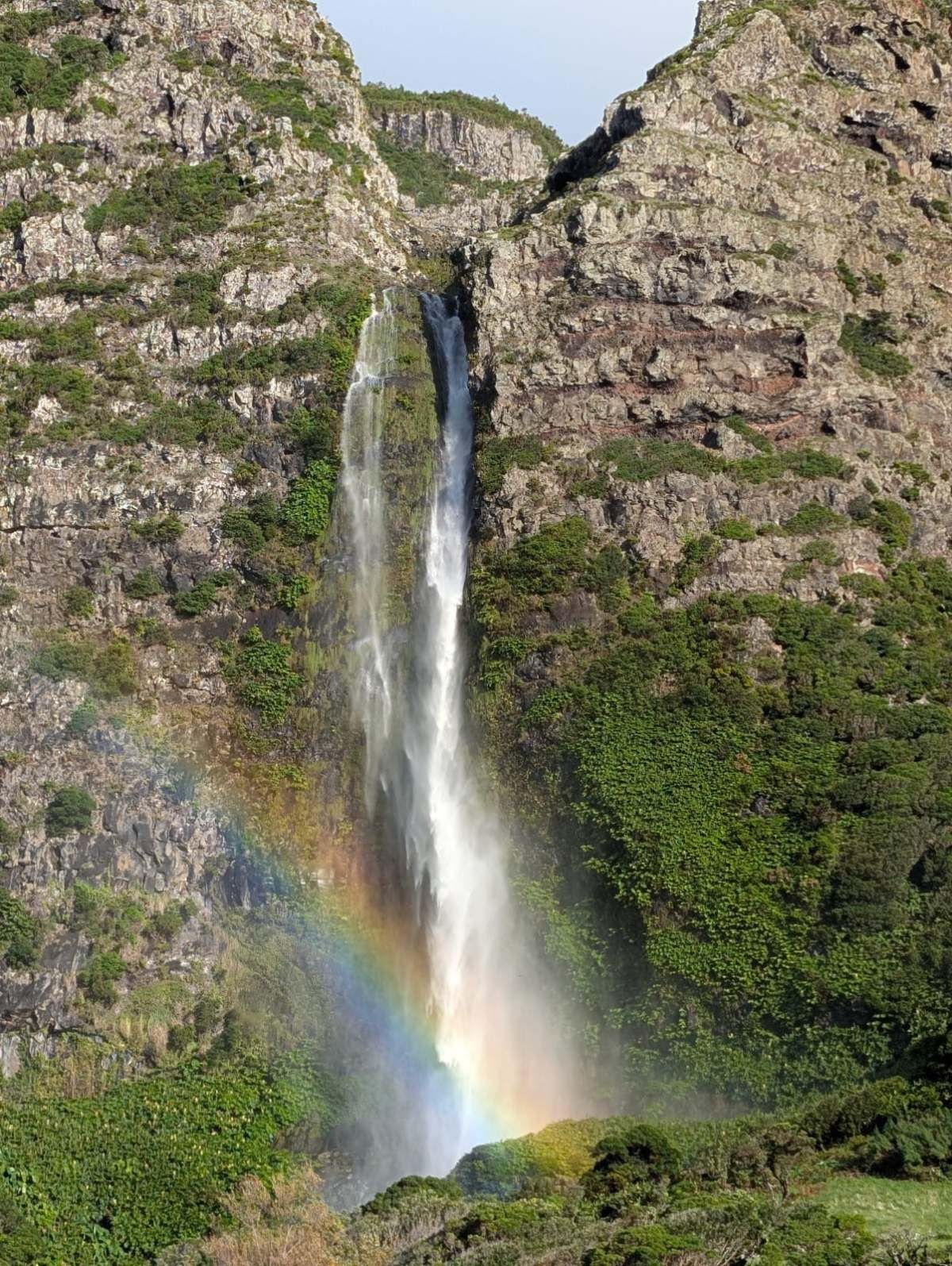 The Poço do Bacalhau waterfall with a rainbow in its spray